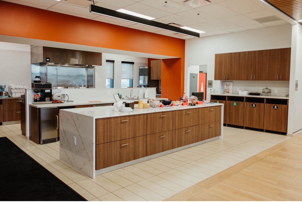 Volunteer kitchen where volunteers prepare at least one hot meal a day for families; white walls with bright orange accents and white marble counters.