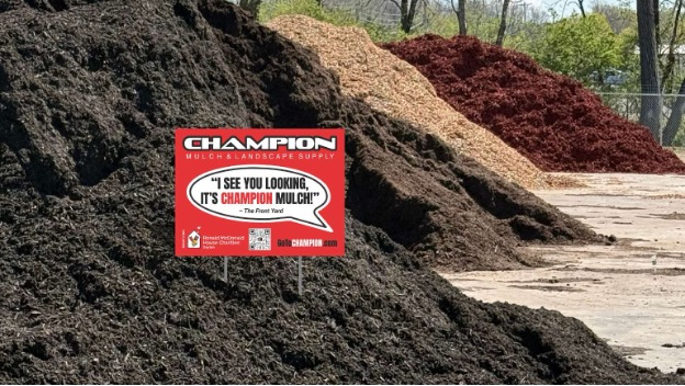 Champion Mulch yard sign, displayed in front of mulch piles.